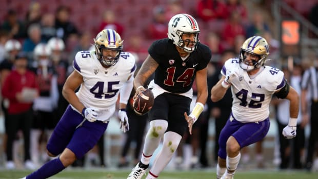 Oct 28, 2023; Stanford, California, USA; Stanford Cardinal quarterback Ashton Daniels (14) scrambles away from defensive pressure by Washington Huskies edge rusher Maurice Heims (45) and linebacker Carson Bruener (42) during the first quarter at Stanford Stadium.